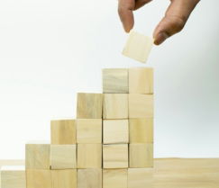 A person placing a piece of wood into a pyramid